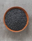 Vue de dessus des lentilles de béluga noires biologiques dans un plat en terre cuite — Photo de stock