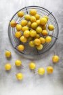 Yellow plums in wire basket — Stock Photo