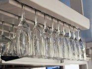 Vista de perto de taças de champanhe e vinho penduradas de cabeça para baixo em uma prateleira do restaurante — Fotografia de Stock