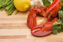 Steamed lobster with lemons and fresh vegetables  over wooden surface — Stock Photo