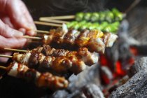 Closeup cropped view of hands grilling Yakitori skewers — Stock Photo