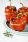 Red peppers stuffed with barley and rosemary on blue plate — Stock Photo