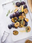Halved Damsons with rosemary — Stock Photo