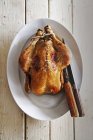 Roasted chicken with knives — Stock Photo