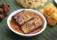 Nyonya-Küche: Auberginen in Curry-Kokos-Sauce auf weißem Teller — Stockfoto