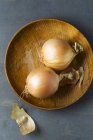 Onions on wooden plate — Stock Photo