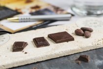 Grãos de cacau e vários pedaços de chocolate — Fotografia de Stock