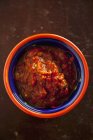 Пряный томатный соус в миске над деревянной поверхностью — стоковое фото