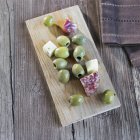 Зеленые оливки на деревянной доске — стоковое фото