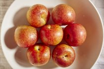 Ameixas vermelhas maduras na tigela — Fotografia de Stock