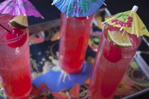Closeup view of three Singapore Slings with paper umbrellas on a tray — Stock Photo