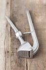 Closeup view of garlic press on wooden surface — Stock Photo