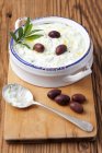 Tzatziki with olives in dish  over wooden surface — Stock Photo
