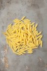 Dry uncooked pile of penne pasta — Stock Photo