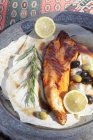 Grilled sturgeon with olives and lemon on plate over cloth — Stock Photo