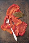 Маринованный красный перец на металлической поверхности с вилкой — стоковое фото
