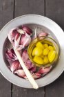 Aglio conservato in olio d'oliva su piatto bianco — Foto stock