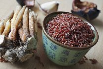 Fingerwurzeln und Schüssel mit rotem Reis — Stockfoto