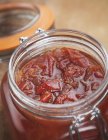 A jar of tomato chutne  over blurred  wooden surface — Stock Photo