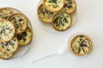 Mini spinach and mushroom quiches on white surface — Stock Photo