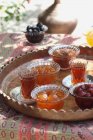Verres de thé et conserves confites fruits sur une table à l'extérieur — Photo de stock