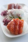 Sashimi on strips of radish with seaweed on white plate — Stock Photo