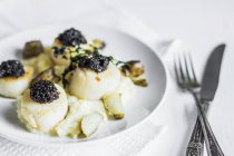 Vista close-up de vieiras fritas com caviar preto e erva na placa — Fotografia de Stock
