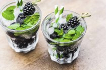 Closeup view of two glasses of water with blackberries, ice cubes and mint — Stock Photo