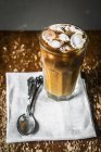 Closeup view of iced coffee in glass with spoons on cloth — Stock Photo