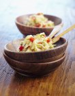 Salade de chou courgette aux poivrons coupés en dés dans des bols en bois sur une surface en bois — Photo de stock