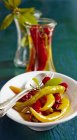 Sweet-and-sour pickled peppers on white plate with fork and spoon — Stock Photo