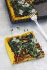 Polenta spinach tart with tomato pesto on dish and on marble surface with fork — Stock Photo