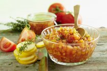 Courgette and tomato chutney with ingredients over wooden surface — Stock Photo