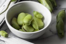 Fresh fava beans in white bowl — Stock Photo