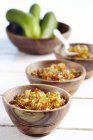 Cucumber relish with peppers in wooden bowls over wooden surface — Stock Photo