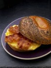 Closeup view of scrambled egg and bacon on a poppy seed roll — Stock Photo