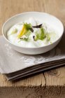 Tzatziki con cetriolo, limoni e aneto su piatto bianco sopra asciugamano — Foto stock