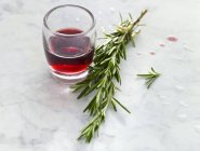 Copa de vino tinto y una ramita de romero - foto de stock