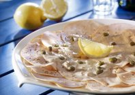 Closeup view of turkey Tonnato with lemon and nuts — Stock Photo