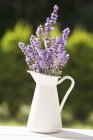 Closeup daytime view of a jug of lavender on a garden table — Stock Photo