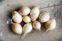 Onions on wooden surface — Stock Photo