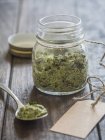 Vista close-up de ervas vegan Pesto em um frasco e em uma colher — Fotografia de Stock