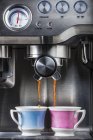 Приготовление кофе в чашках с кофеваркой — стоковое фото