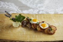Tiroler - typical Tirolean dish using leftovers with quail eggs and fresh marjoram on wooden desk — Stock Photo