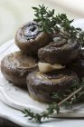 Marinated mushrooms with fresh thyme, black caraway and garlic on white plate — Stock Photo