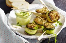 Capesante avvolte in zucchine con aioli su piatto bianco — Foto stock