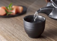Nahaufnahme des Gießens dampfenden Wassers auf schwarze Tasse — Stockfoto
