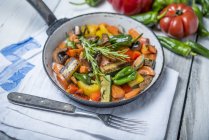 Fried vegetables with mushrooms and rosemary on pan over towel — Stock Photo