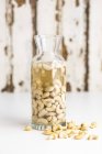 Closeup view of soften cashew nuts in carafe and on white surface — Stock Photo