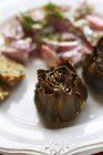 Oven-roasted artichokes on white plate with blurred background — Stock Photo
